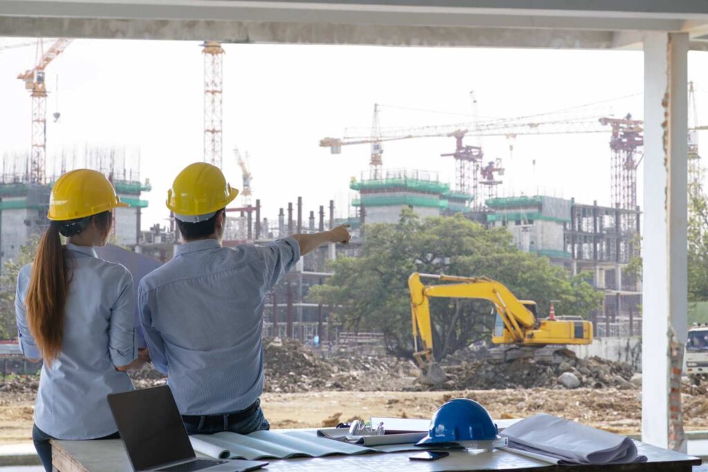 Engineer group and worker meeting, discussion with construction blueprint on residential construction in Mumbai site work and point finger to the work site